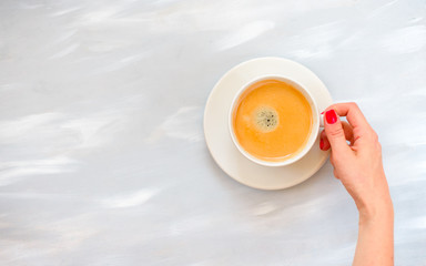 Woman hands with red manicure holding coffee cup on table, top view with copy space