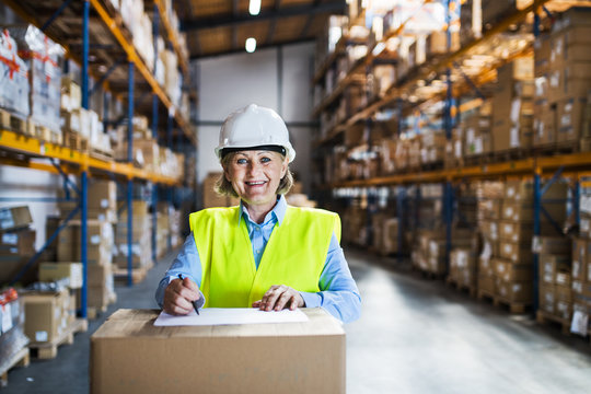 A senior woman warehouse worker or supervisor controlling stock.