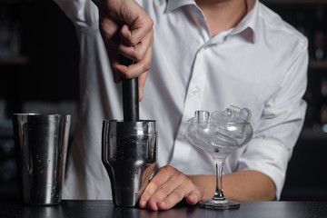 Close-up of barmen squeezes fresh fruits in the shaker by the madler.