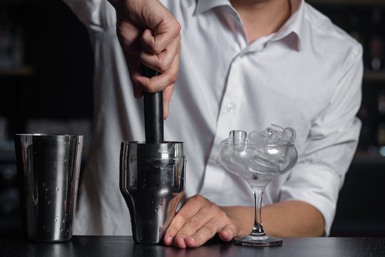 Close-up of barmen squeezes fresh fruits in the shaker by the madler.