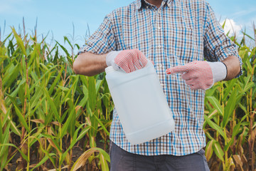 Farmer holding pesticide chemical jug in cornfield