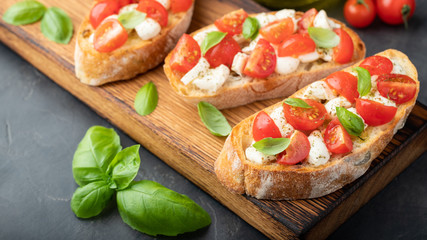 Bruschetta with tomatoes, mozzarella cheese and basil on a cutting board. Traditional italian appetizer or snack, antipasto