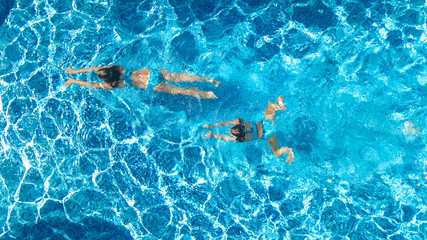 Aerial top view of girls in swimming pool water from above, active children swim, kids have fun on...