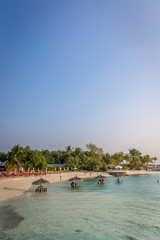 Maldives, Feb 8th 2018 - Tourists enjoying the swimming pool area and the beach area of a resort in Maldives, afternoon lights, some trees and table.