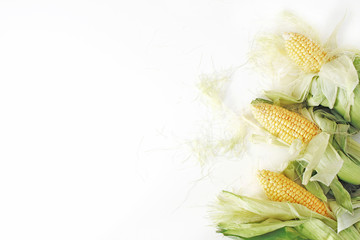 Fresh yellow sweet corn cobs on white table background. Vegetable decorative frame composition, web banner. Flat lay, top view.