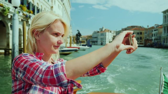 Grand Canal cruise. Young woman takes pictures of beautiful views of Venice in Italy.