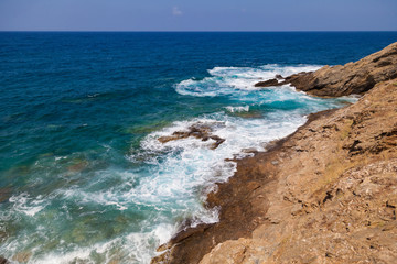 Fototapeta na wymiar Blue sea waves on a rocky beach, Crete, Greece. Mediterranean coast. Travel and vacation on the beach. Beautiful seascape..