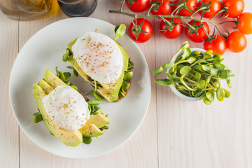 Avocado toast, cherry tomato and poached eggs on wooden background. Breakfast with vegetarian food, healthy diet concept.