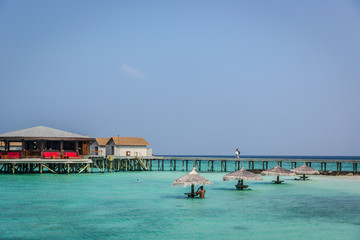 Maldives, Feb 8th 2018 - Tourists enjoying a calm beach, blue water, tropical climate, no waves in a blue sky day in Maldives.