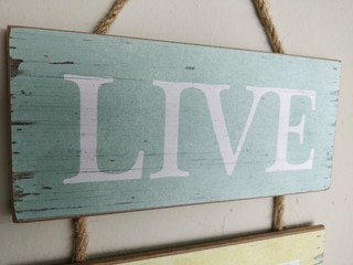 A wooden sign with the word "LIVE" painted on it, hanging on the wall