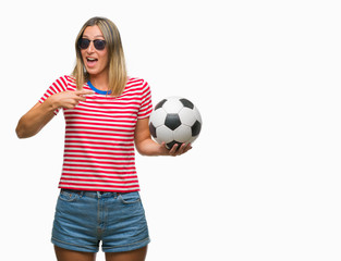 Young beautiful woman holding soccer football ball over isolated background very happy pointing with hand and finger