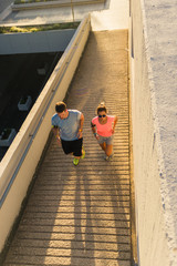 Athletic couple running on sunset in the city