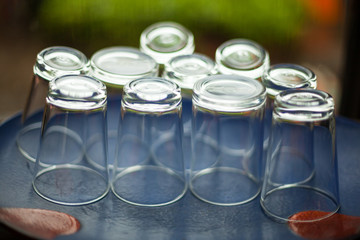 water drinking glasses upside down on the blue tray floor background. Liquid container, service industry concept.