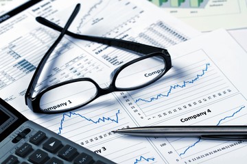 Glasses, Pen And Calculator On Financial Graphs Close-up