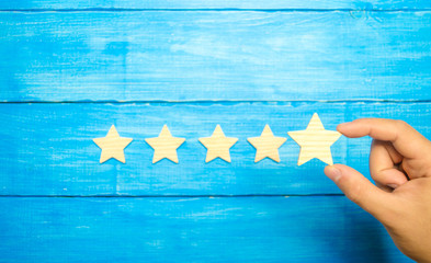 The businessman's hand in the suit holds the fifth star. Get the star. concept of the rating of...