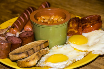 full Irish breakfast high-calorie french bean sausage toast bacon on a wooden background