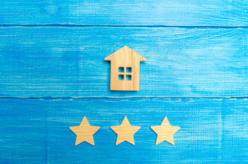 Fototapeta na wymiar Wooden house and three stars on a blue background. Rating of houses and private property. Buying and selling, renting apartments. The level of the restaurant and hotels. Rating five stars.