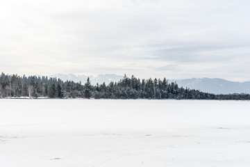 Frozen Kirchsee lake, Bavaria, with Alps in background, in winter