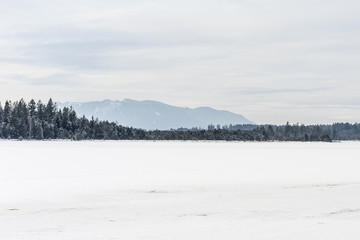 Frozen Kirchsee lake, Bavaria, with Alps in background, in winter