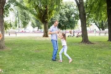 daughter and mother spinning on the lawn.in a white t-shirt and jeans. a walk in the Park. child. mother-daughter. summer.