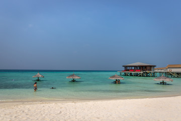 Maldives, Feb 8th 2018 - Tourists enjoying a calm beach, blue water, tropical climate, no waves in a blue sky day in Maldives.