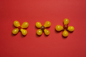 Creative flower food background. Yellow cherry tomatoes on red background top view
