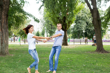 Naklejka na ściany i meble man and woman sitting on the lawn. in a white t-shirt and jeans. a walk in the Park. lover. young couple. summer. family. embrace 