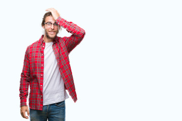 Young handsome man with long hair wearing glasses over isolated background surprised with hand on head for mistake, remember error. Forgot, bad memory concept.