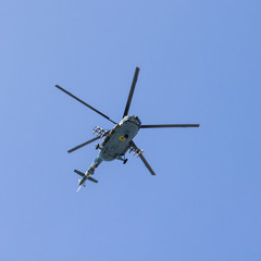 Military helicopter maneuvers in the blue sky
