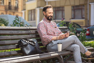 Obraz premium Handsome smiling man using his smartphone outdoors