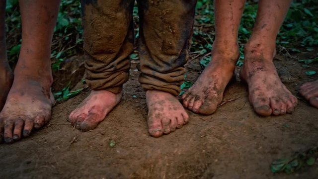 Close-up barefooted dirty feet of a children standing on a damp ground