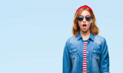 Young beautiful woman over isolated background wearing sunglasses afraid and shocked with surprise expression, fear and excited face.