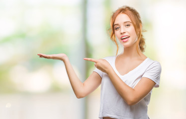 Young beautiful woman over isolated background amazed and smiling to the camera while presenting with hand and pointing with finger.