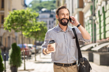 Joyful adult man talking on his phone outdoors