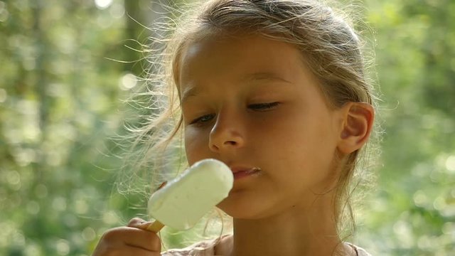 Little girl licking ice-cream. Charming child eats ice cream outdoors
