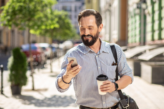 Cheerful adult man using his smartphone outdoors