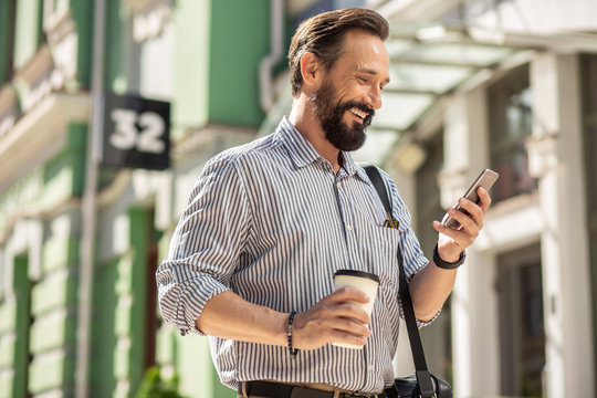 Positive adult man drinking coffee on his way to work
