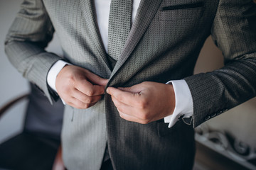 Grooms morning preparation, handsome groom getting dressed and preparing for the wedding, in dark blue suit.