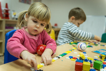 Caucasian boy and girl playing with wooden toy in kindergarten