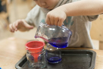 Little caucasian boy playing with paints in kindewrgarten