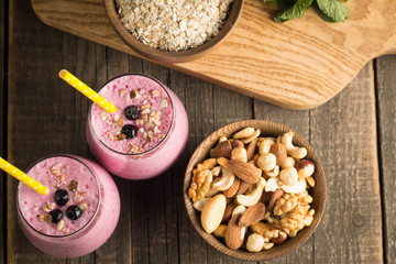 Glasses of berry smoothie with nuts, mint, blueberry, blackberry, raspberry, and yogurt on wooden table. Weight loss and diet concept. 