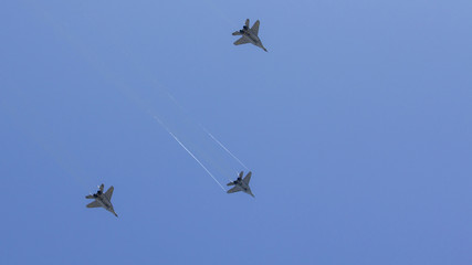 Several military fighters are flying in a formation against the blue sky