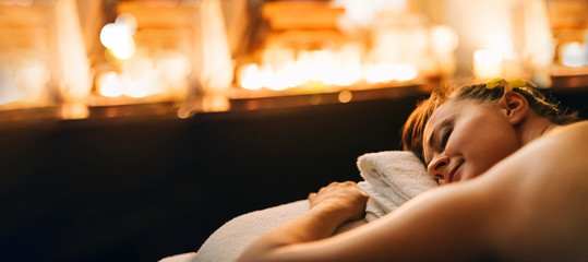 Woman having thai massage on bed with candles enjoying relaxing background