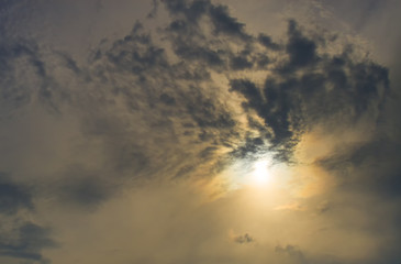 Sun rising behind the dark clouds, dark orange tone.