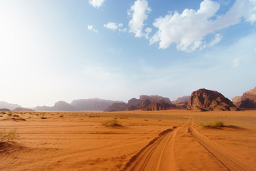 Fototapeta na wymiar Wadi Rum desert, Jordan, Middle East, known as The Valley of the Moon. Orange sand, blue sky, haze and clouds. Designation as a UNESCO World Heritage Site. Red planet Mars landscape.