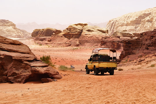 Offroad Travel Adventures Safari Jeep Car In Wadi Rum Desert, Jordan, Middle East, Known As The Valley Of The Moon. Red Sands, Sky With Haze. Designation As A UNESCO World Heritage Site.