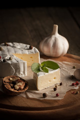 Camembert and brie cheese on wooden background with tomatoes, letuce and garlic. Italian food. Dairy products.