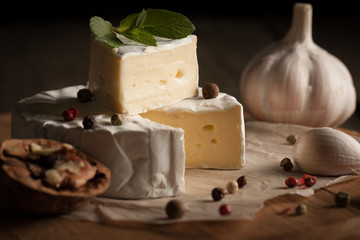 Camembert and brie cheese on wooden background with tomatoes, letuce and garlic. Italian food. Dairy products.