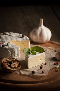 Camembert and brie cheese on wooden background with tomatoes, letuce and garlic. Italian food. Dairy products.
