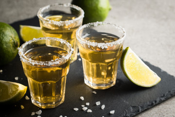Macro photo of shots of gold Mexican tequila with lime and salt on wooden rustic background. Alcoholic drink concept. selective focus.
